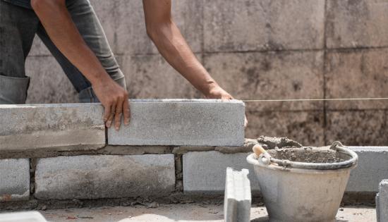 A construction worker builds a wall with concrete and mortar