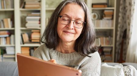 A woman is smiling while scrolling on her iPad